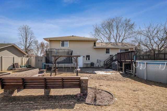 back of house featuring a fenced in pool, fence, a garden, a deck, and a trampoline