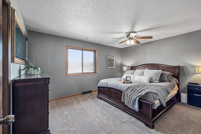 bedroom with visible vents, a textured ceiling, carpet, baseboards, and ceiling fan