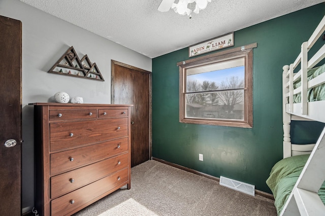 bedroom with visible vents, baseboards, light colored carpet, a textured ceiling, and a ceiling fan