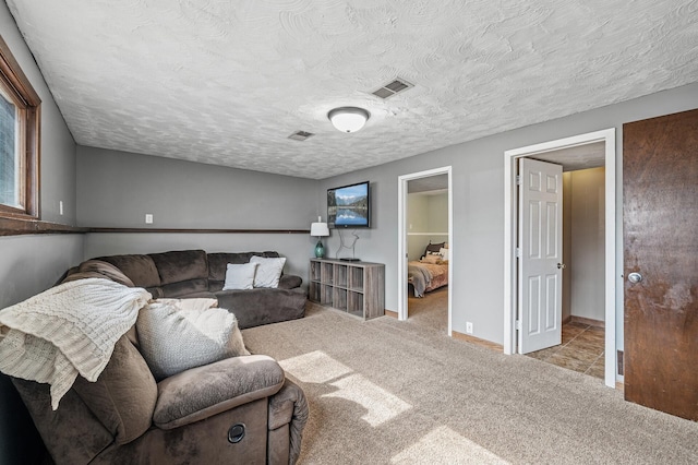 living room with baseboards, carpet, visible vents, and a textured ceiling