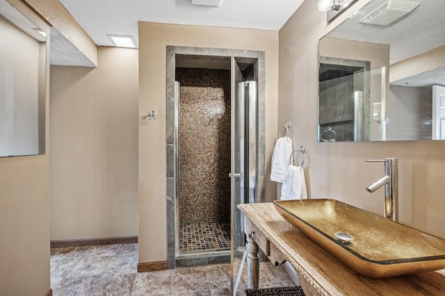 bathroom with a shower stall, baseboards, visible vents, and a sink