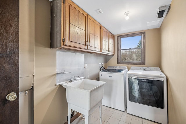 washroom with visible vents, a sink, cabinet space, light tile patterned flooring, and washing machine and clothes dryer