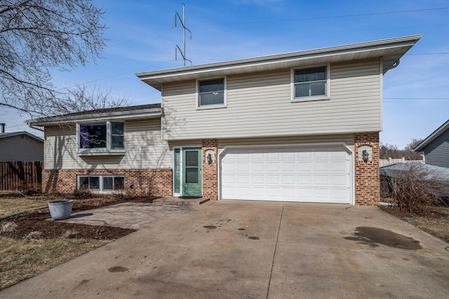 tri-level home featuring brick siding, an attached garage, driveway, and fence