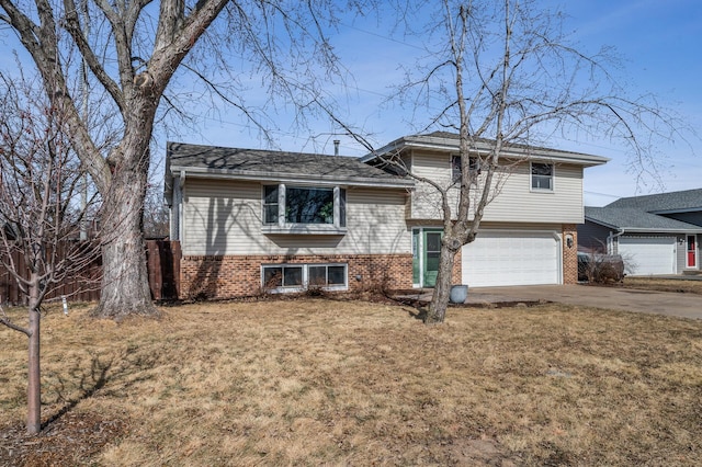 split level home featuring a front yard, an attached garage, brick siding, and driveway