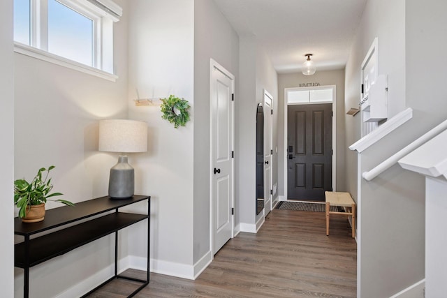 foyer entrance with stairs, wood finished floors, and baseboards