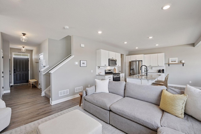 living area featuring visible vents, recessed lighting, and stairs