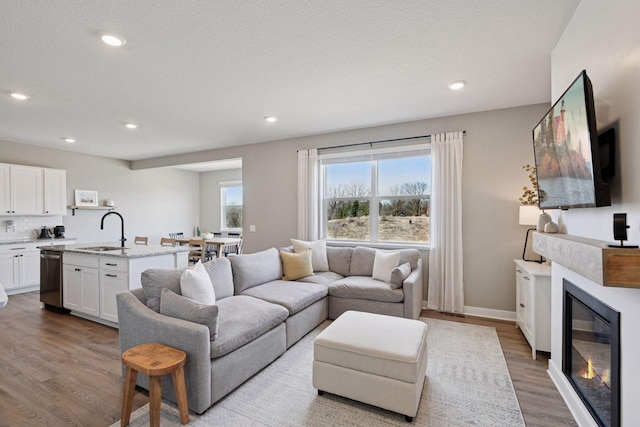 living area with recessed lighting, wood finished floors, and a glass covered fireplace