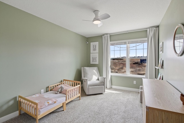 carpeted bedroom featuring a ceiling fan, baseboards, and a textured ceiling