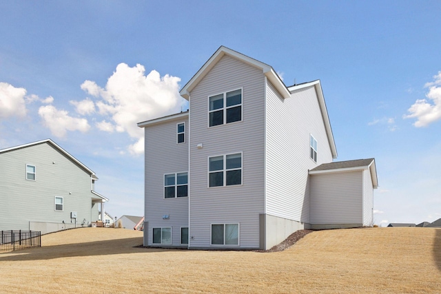 back of property featuring a lawn and fence