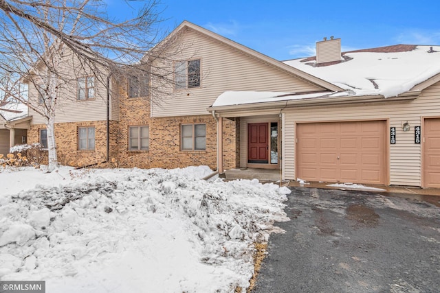 multi unit property with a garage, brick siding, and a chimney