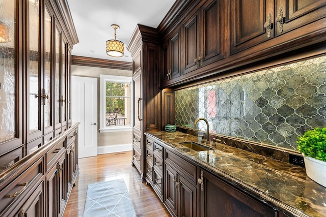 2427 Lake Of The Isles Pkwy, Minneapolis, MN 55405 - kitchen featuring a sink, baseboards, dark stone counters, dark brown cabinets, and pendant lighting