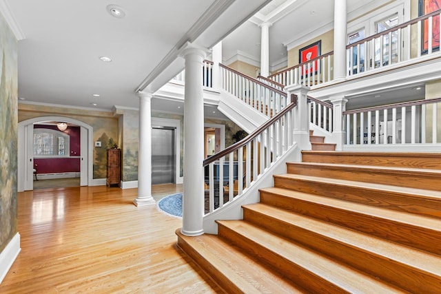 2427 Lake Of The Isles Pkwy, Minneapolis, MN 55405 - staircase with ornamental molding, decorative columns, wood finished floors, a baseboard heating unit, and arched walkways
