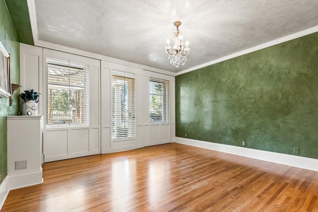2427 Lake Of The Isles Pkwy, Minneapolis, MN 55405 - unfurnished room featuring wood finished floors, a chandelier, a decorative wall, and ornamental molding