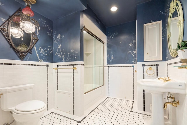 2427 Lake Of The Isles Pkwy, Minneapolis, MN 55405 - bathroom featuring tile walls, wainscoting, toilet, enclosed tub / shower combo, and tile patterned flooring