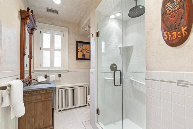 2427 Lake Of The Isles Pkwy, Minneapolis, MN 55405 - full bathroom featuring radiator, tile walls, wainscoting, a shower stall, and vanity