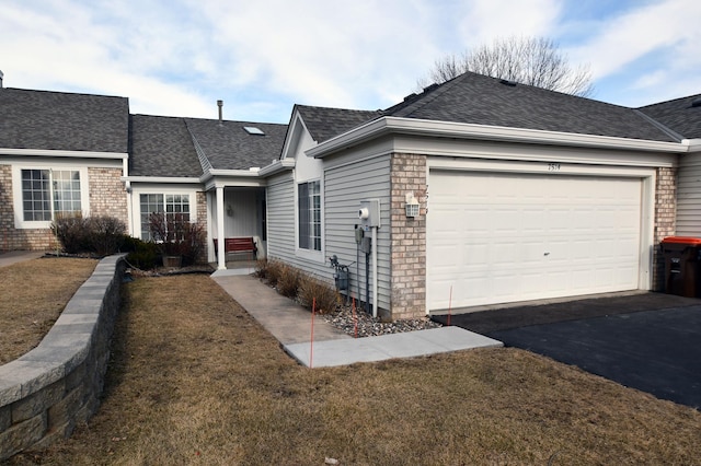 single story home featuring a shingled roof, an attached garage, brick siding, and aphalt driveway