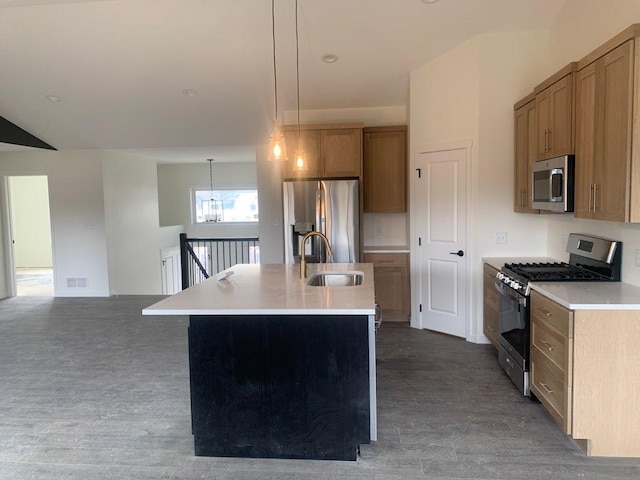 kitchen featuring a center island with sink, appliances with stainless steel finishes, light countertops, pendant lighting, and a sink