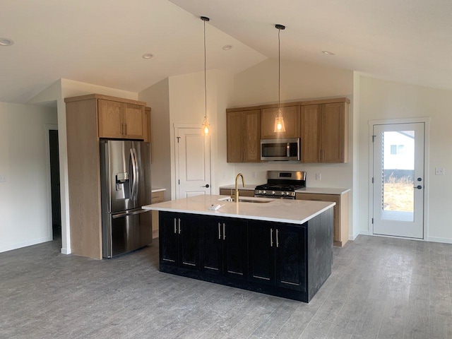 kitchen featuring light wood finished floors, a center island with sink, appliances with stainless steel finishes, light countertops, and a sink