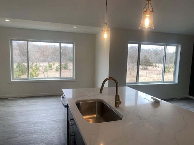 kitchen with hanging light fixtures, recessed lighting, a sink, and light stone countertops