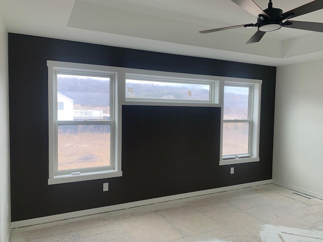 spare room featuring a tray ceiling, visible vents, ceiling fan, and baseboards