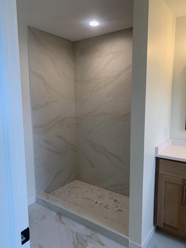 bathroom featuring marble finish floor, a marble finish shower, baseboards, and vanity