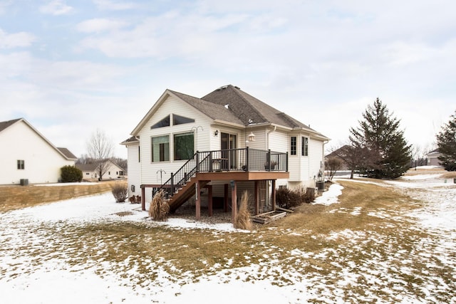 snow covered rear of property with stairway and a deck