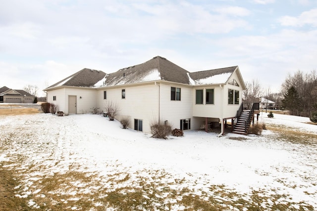 snow covered back of property with stairs