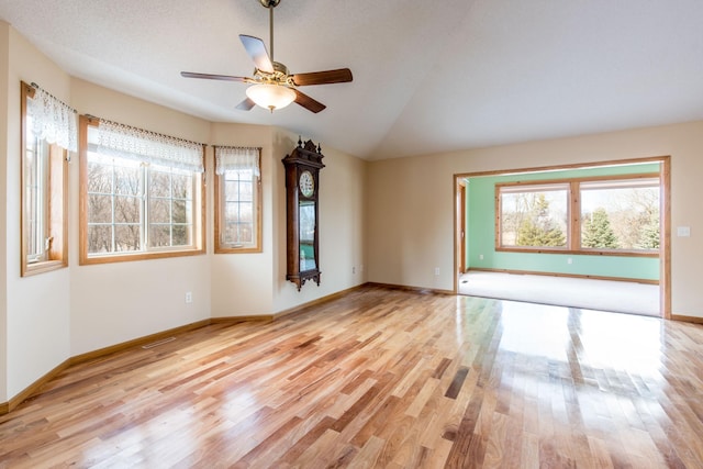 unfurnished room with baseboards, lofted ceiling, visible vents, and wood finished floors