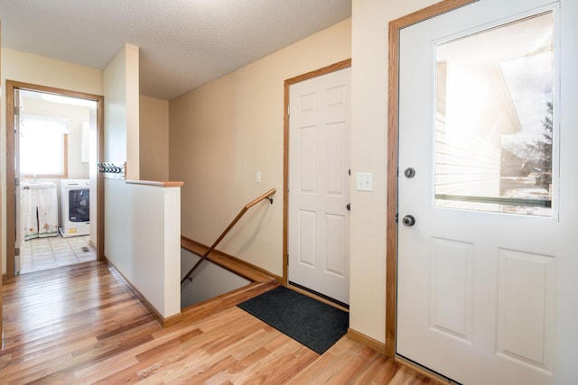 entryway featuring washer / dryer, a textured ceiling, and light wood-style flooring