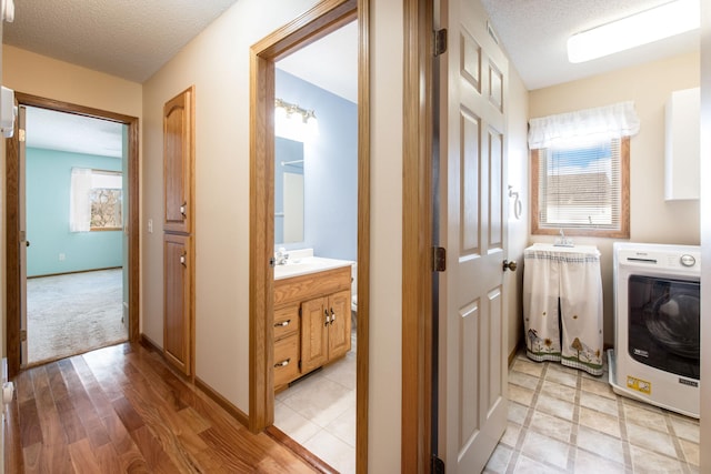 clothes washing area with laundry area, washer / clothes dryer, baseboards, and a textured ceiling