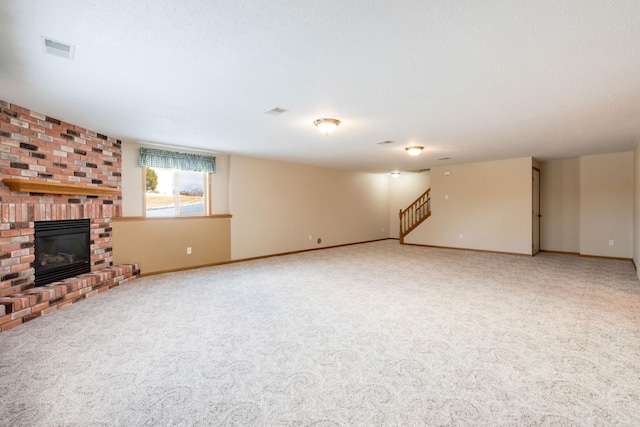 unfurnished living room with visible vents, stairway, carpet flooring, baseboards, and a brick fireplace