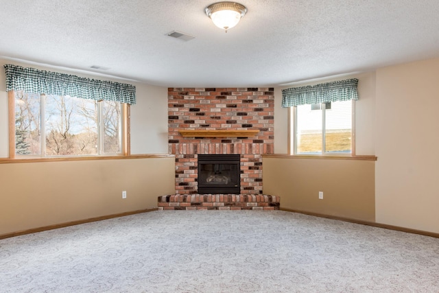 unfurnished living room with a brick fireplace, carpet, visible vents, and baseboards