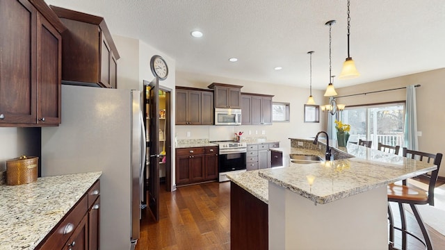 kitchen featuring dark wood-type flooring, a kitchen bar, recessed lighting, appliances with stainless steel finishes, and a sink