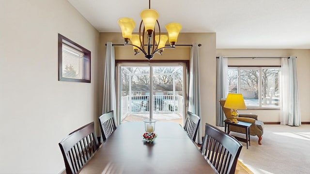 carpeted dining room featuring baseboards and a chandelier