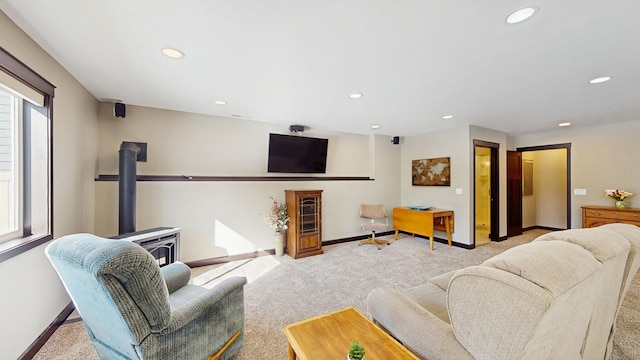 carpeted living area featuring recessed lighting, a wood stove, and baseboards