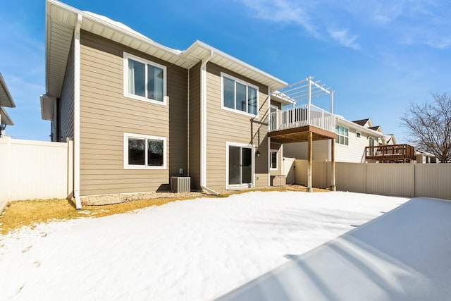 snow covered property featuring cooling unit and fence