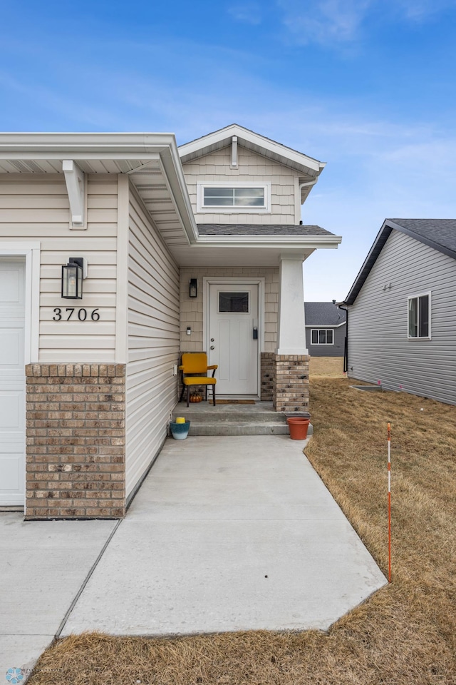 view of exterior entry with brick siding and a garage