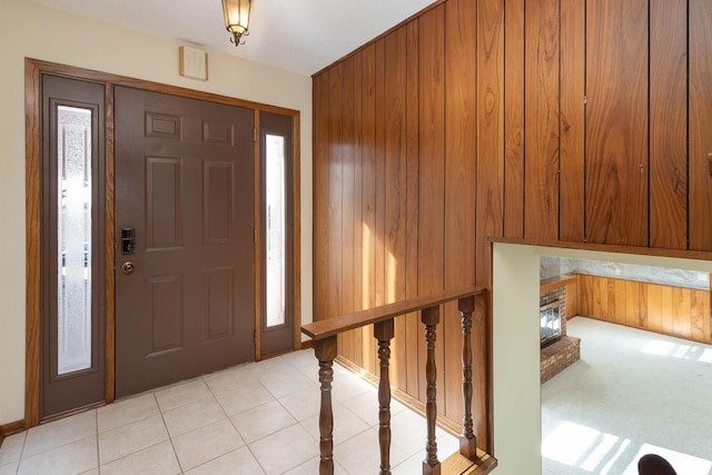 entryway featuring light tile patterned floors, a fireplace, and wood walls