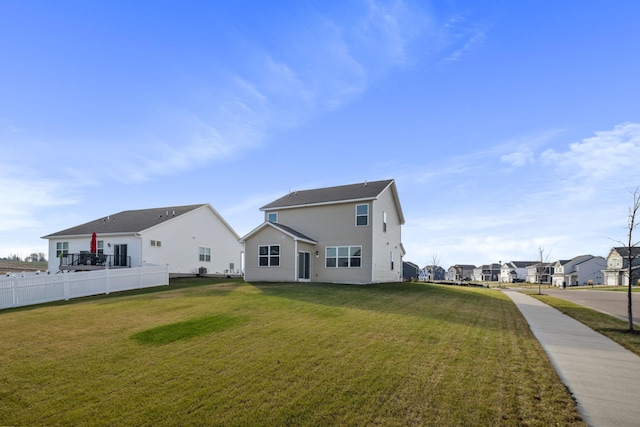 back of house featuring a lawn, fence, and a residential view