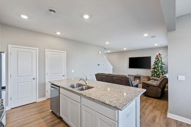 kitchen featuring white cabinetry, a sink, light wood finished floors, and stainless steel dishwasher