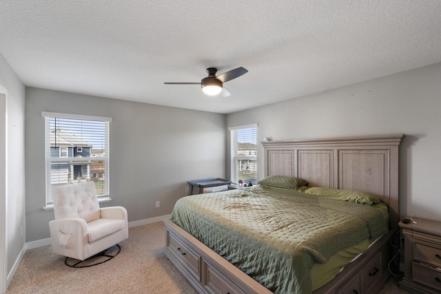 bedroom featuring light carpet, a textured ceiling, and baseboards