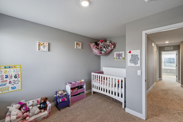 carpeted bedroom featuring a nursery area, visible vents, a textured ceiling, and baseboards