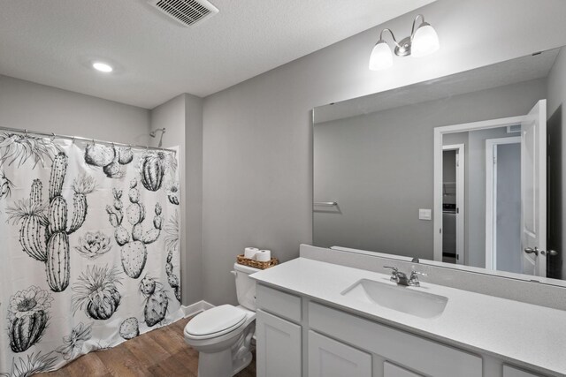 full bathroom featuring visible vents, toilet, wood finished floors, curtained shower, and vanity