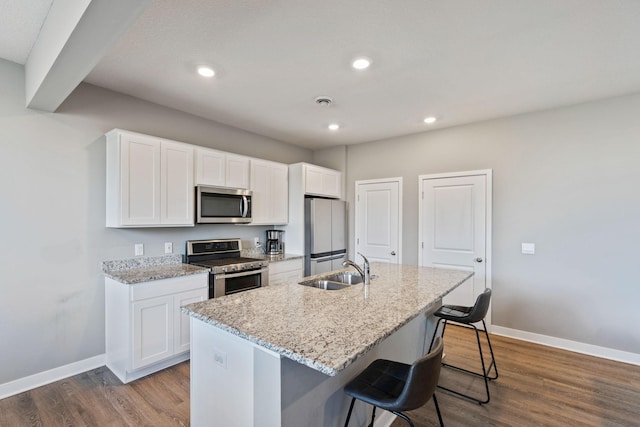 kitchen featuring dark wood-style floors, appliances with stainless steel finishes, an island with sink, and a sink