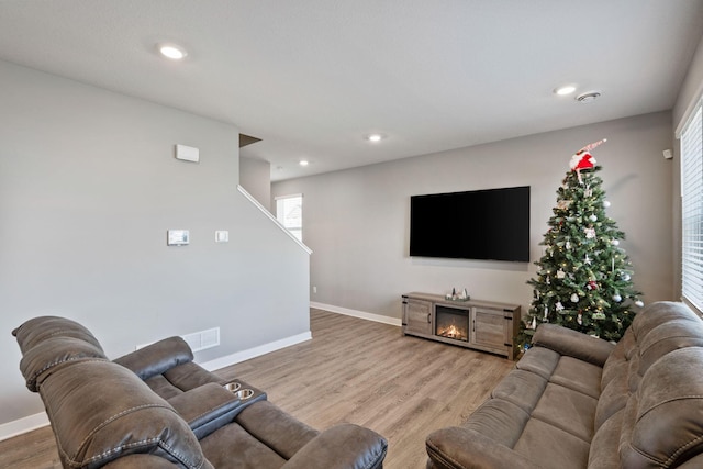 living area with visible vents, baseboards, wood finished floors, a lit fireplace, and recessed lighting