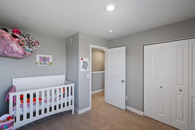 carpeted bedroom featuring baseboards, a textured ceiling, visible vents, and a closet