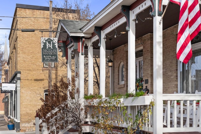 view of side of home with covered porch and brick siding