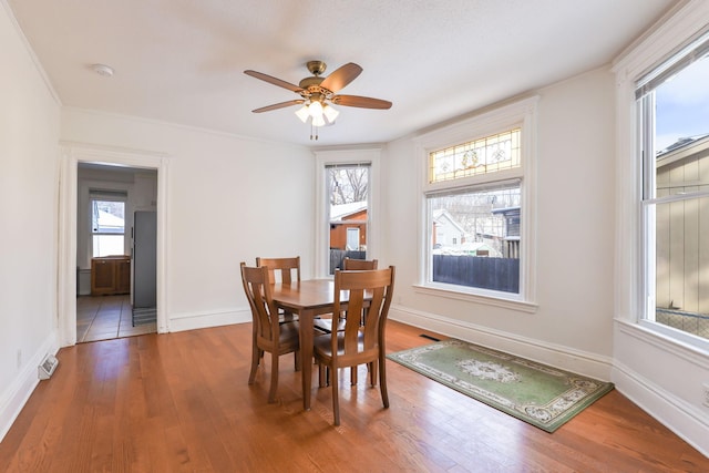 dining room with visible vents, a ceiling fan, baseboards, and wood finished floors