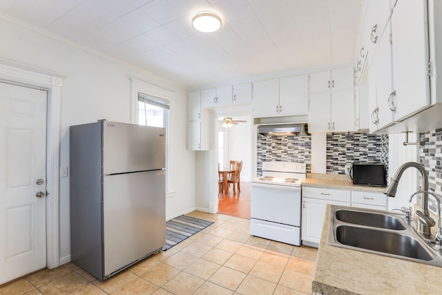 kitchen featuring white range with electric cooktop, a sink, tasteful backsplash, freestanding refrigerator, and exhaust hood