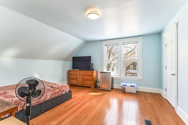 bedroom with light wood-type flooring, lofted ceiling, baseboards, and visible vents